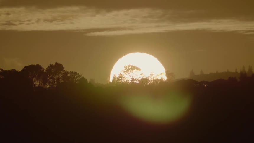 The sun is setting behind the hills ahead