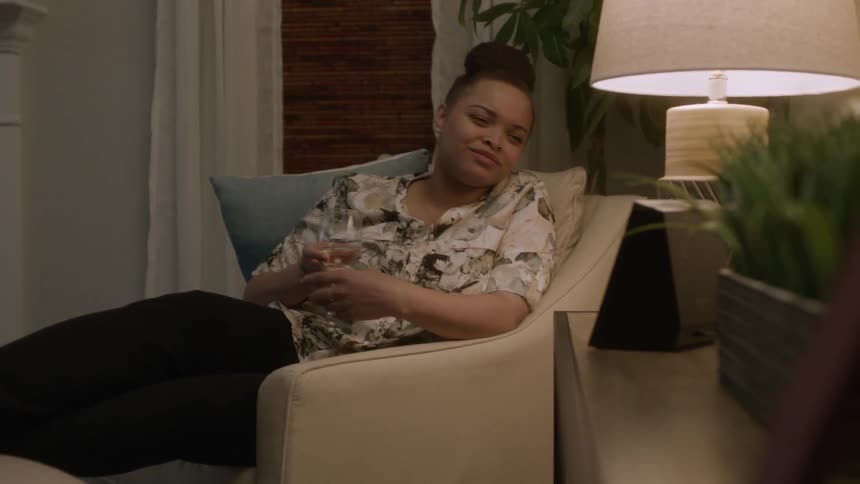 A woman sits on the chair with a drink talking