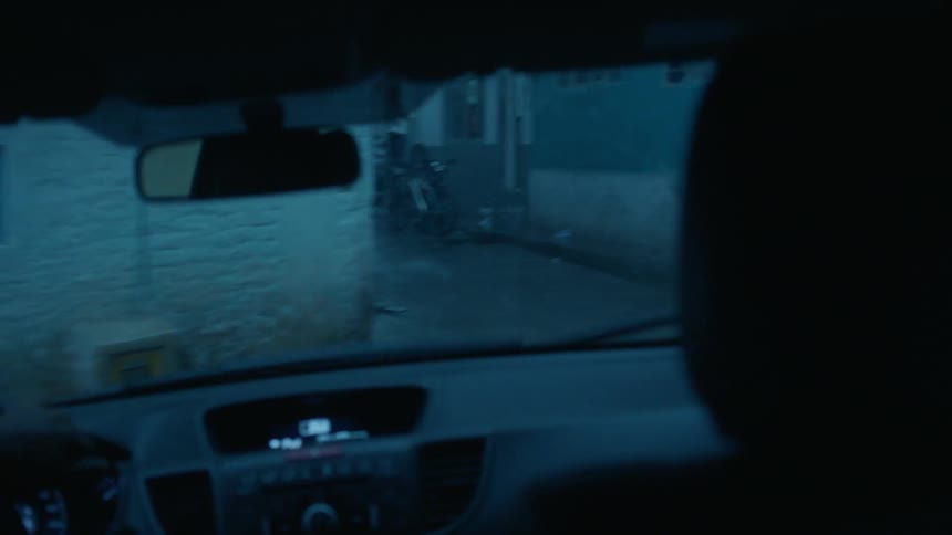 A person drives down narrow roads on a rainy day