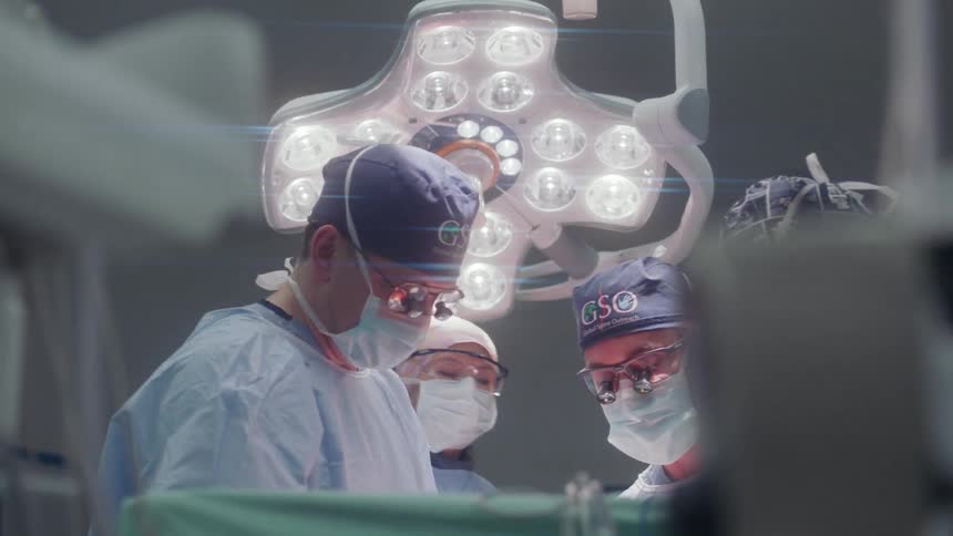 Group of surgeons work under bright lights