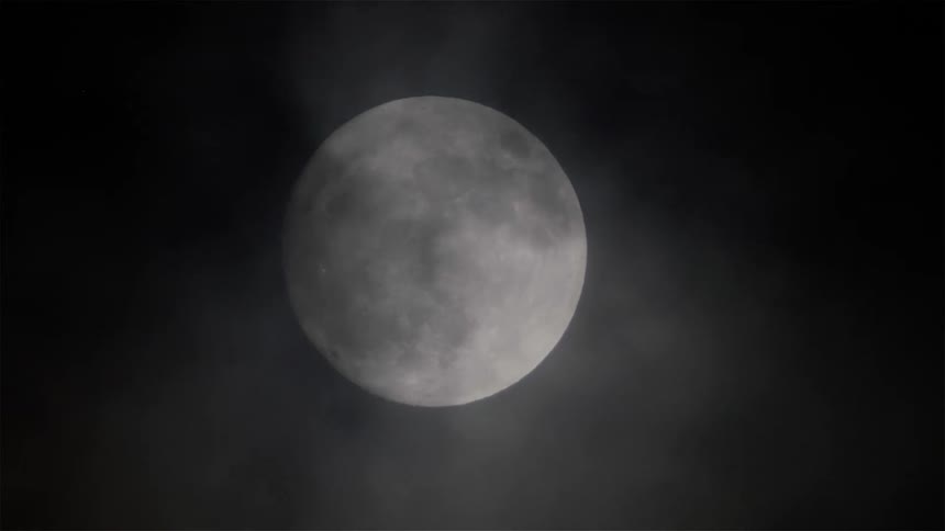 The moon is full with clouds passing over