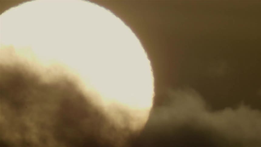 Dark clouds pass in front of the sun