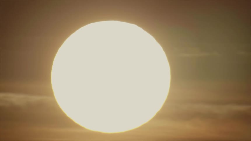 The sun is descending in a cloudy sky at sunset