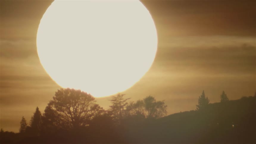 The large sun moves to set behind the hill