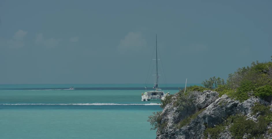 Boat cruises on the water past a larger boat
