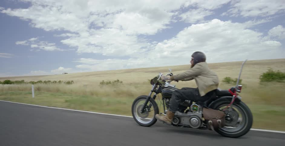 A motorcyclist rides on a rural road