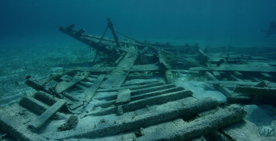 An old shipwreck is decaying beneath the ocean in daylight
