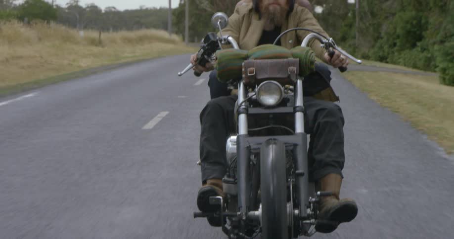 Two people ride a motorcycle on a rural road