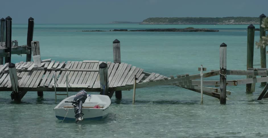 Small boat bobs in the water parked by a dock