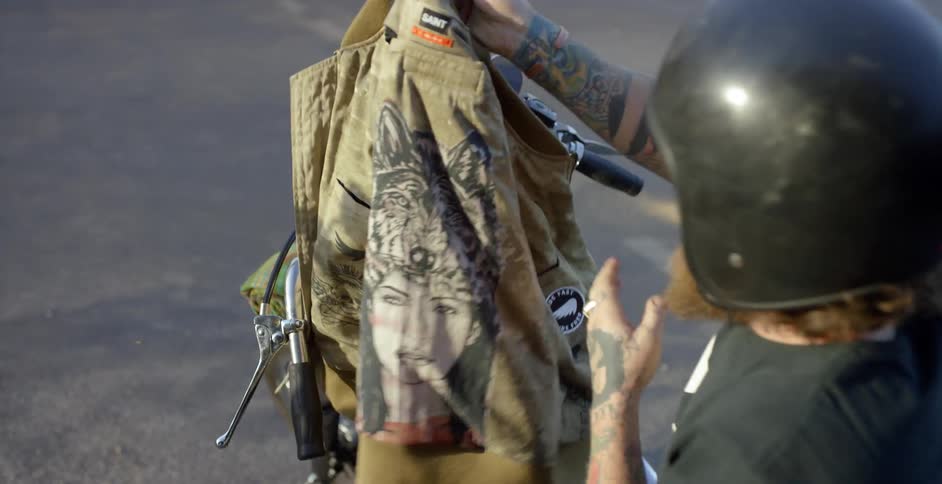 A motorcyclist puts on a helmet and jacket
