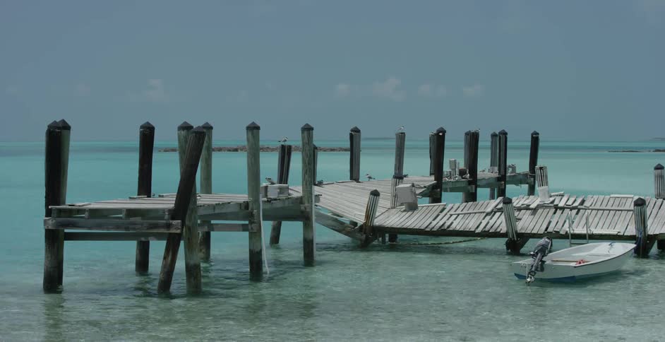 The small boat is parked near the broken pier