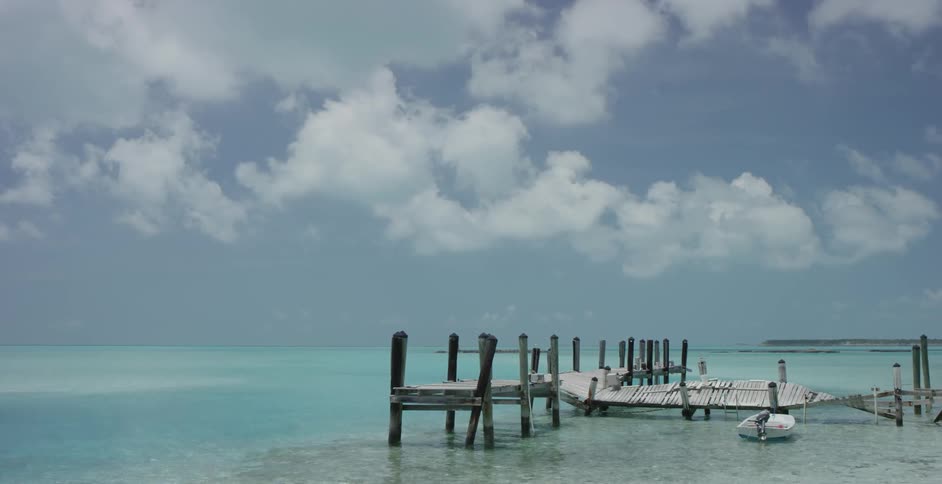Broken pier and a small boat in some clear waters on a cloudy day