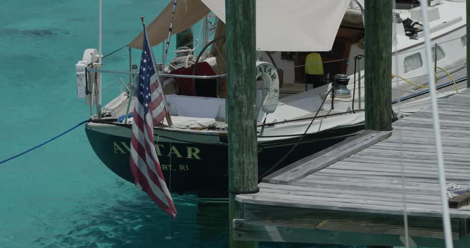 Boat parked at a dock with a flag waving off it in the wind