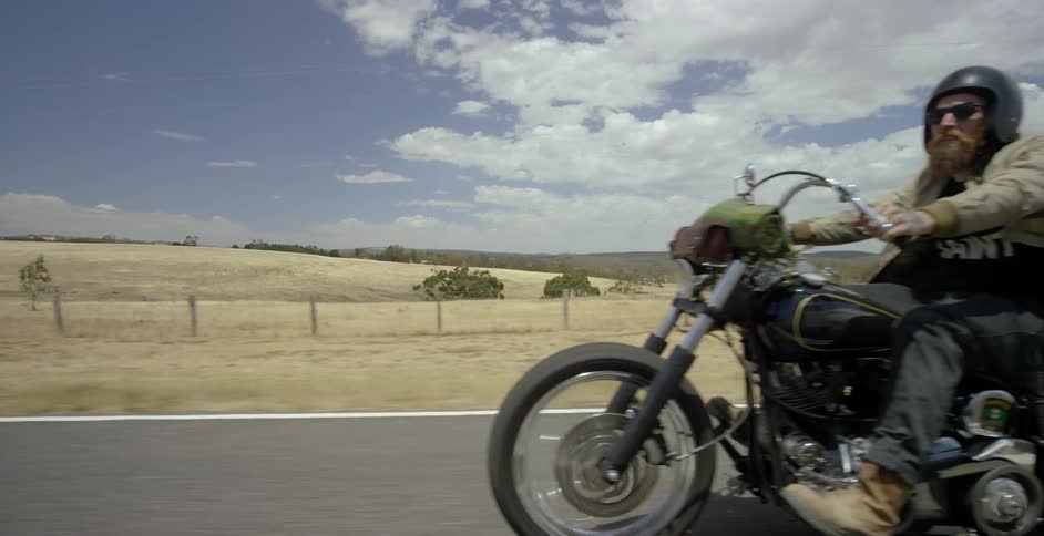 A man rolls up on his motorcycle looking over the field on his side
