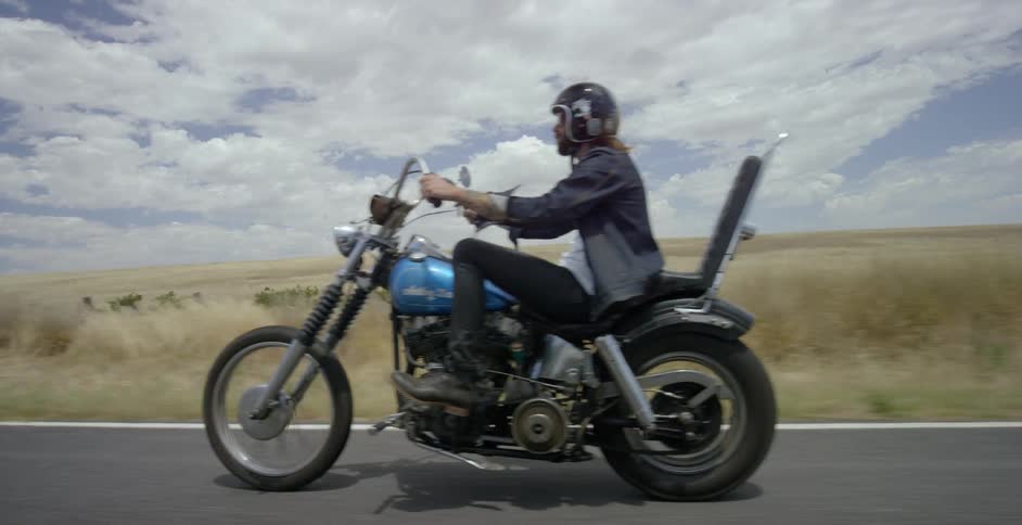 Man rides a motorcycle on a country road