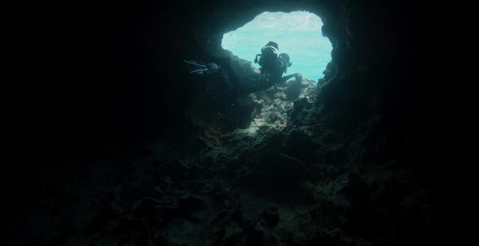 A diver swims out of an underwater cavern