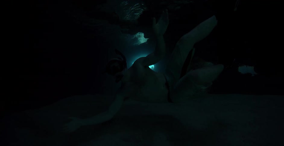 A snorkeler swims underwater in the dark