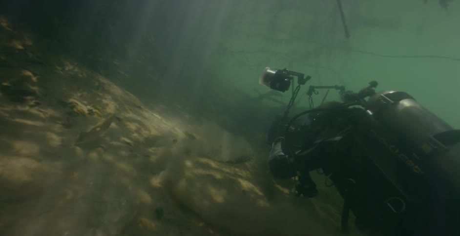 A diver is under the murky waters filming