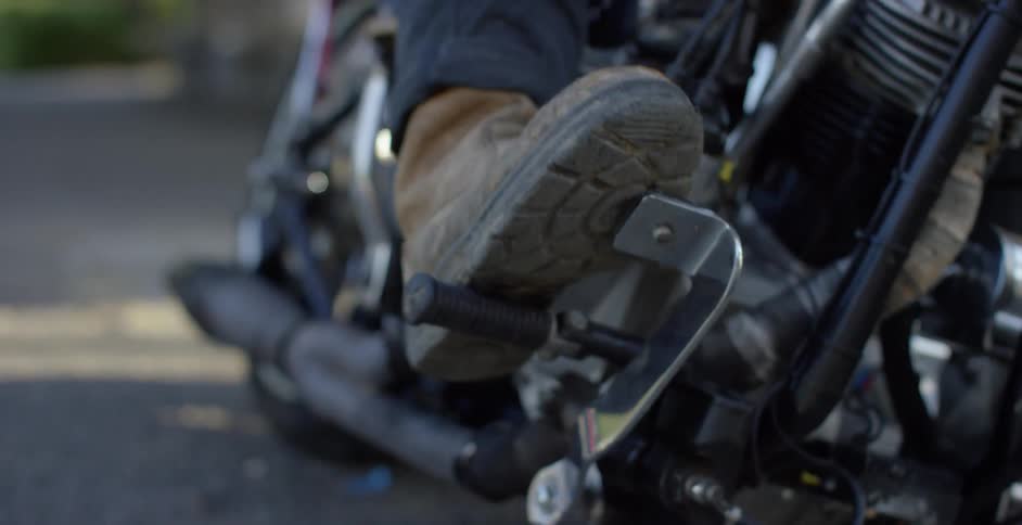 Man puts his foot on the pedal of a motorcycle