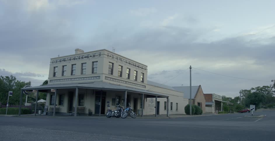 Two motorcycles are parked outside of a building in a rural town