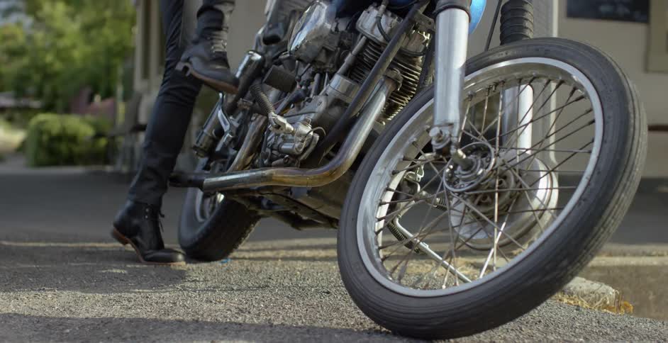 The person is attempting to kickstart a motorcycle