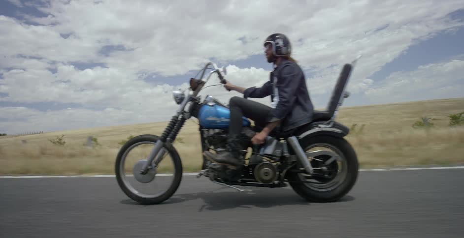 The man rides his motorcycle on the road