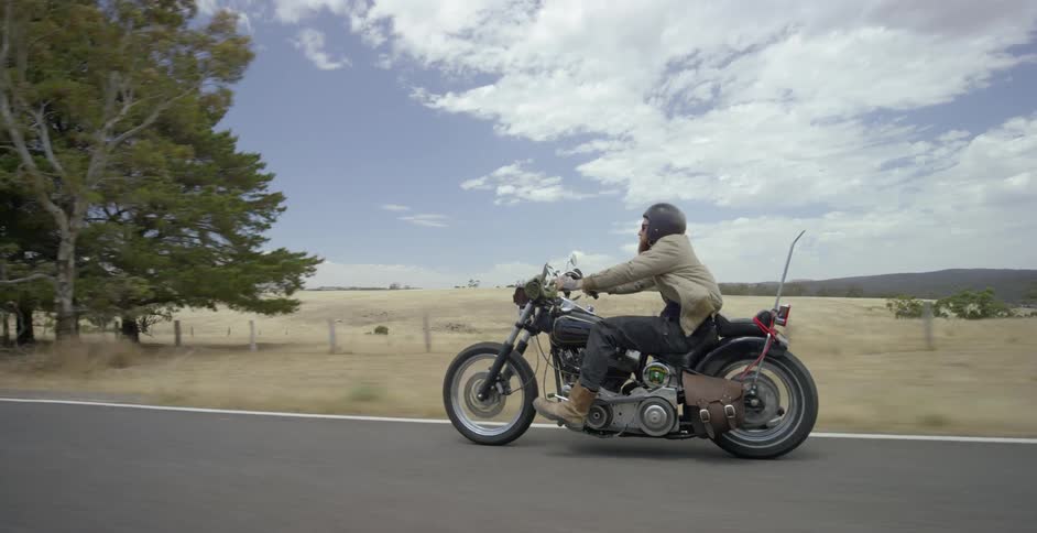 A man rides his motorcycle down the long road