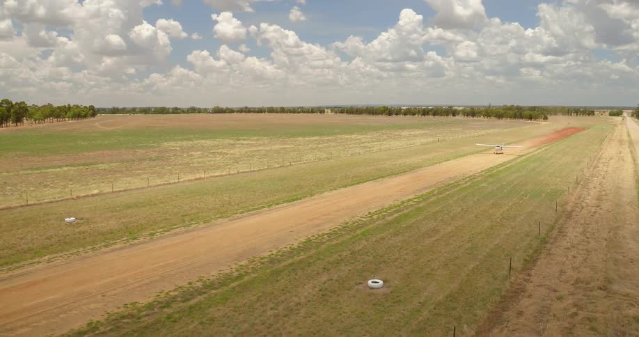 Small airplane travels down a dirt field and takes off