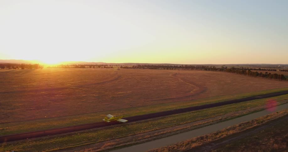 A plane drives across a rural field at sunset