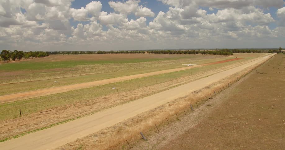 Airplane takes off on a dirt path in a large field