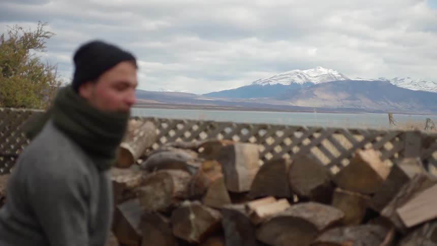 A man sets a log up, and lifts his ax to cut it