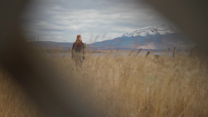 A woman looks to the side near the lake on a windy day