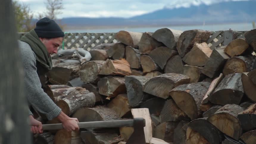 A man is cutting wood in his yard