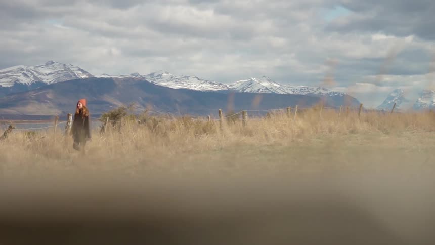 A woman walks across a rural field