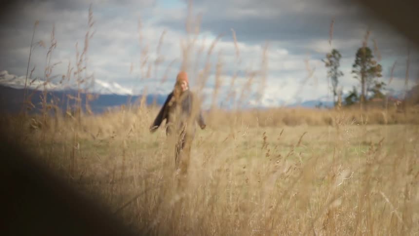 A woman walks in a rural grassy field