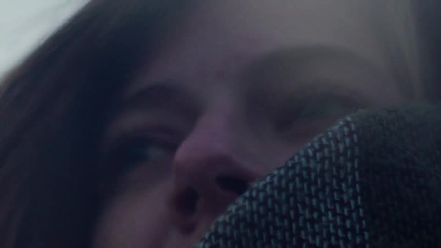 A woman is wrapped in a blanket outside on a breezy day