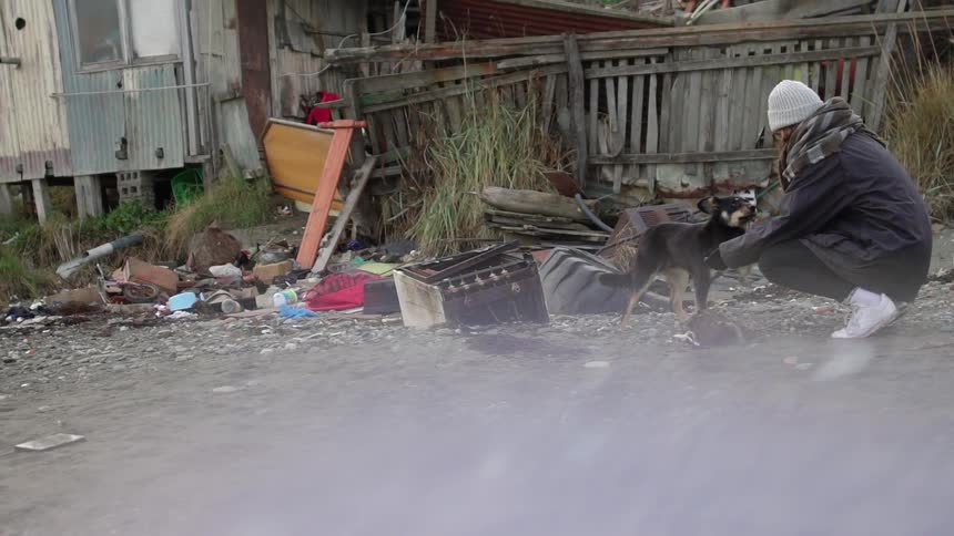 A woman pets a dog near trash outside