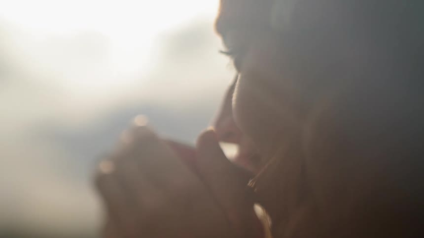 Smiling woman takes a drink from a mug on a sunny day