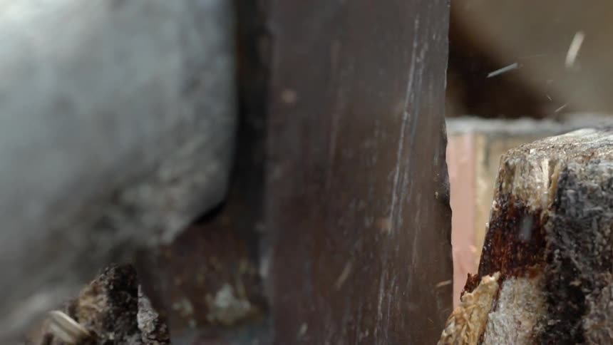 A log falls away after an ax cuts into it