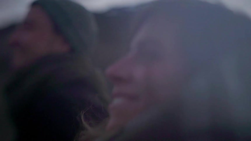 A man and woman smile while hiking in mountains