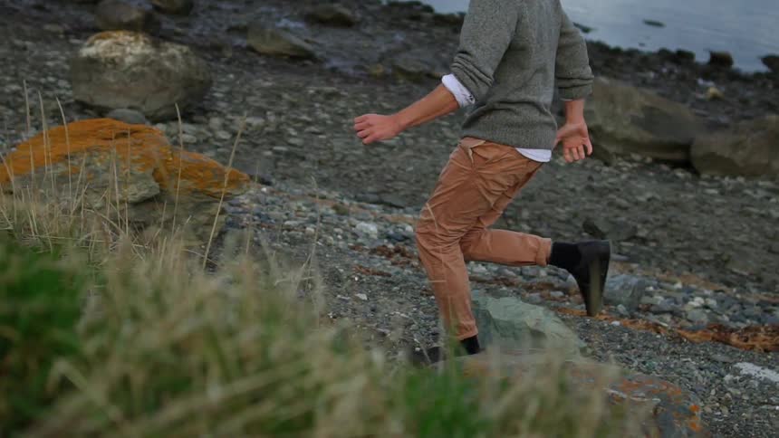 A man runs on a rocky lakeshore