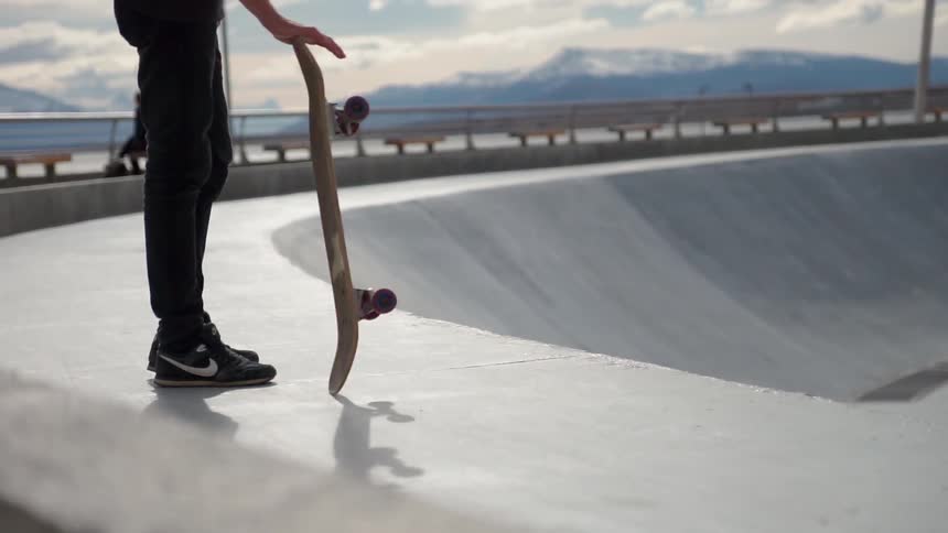 A skateboarder stands in a skatepark