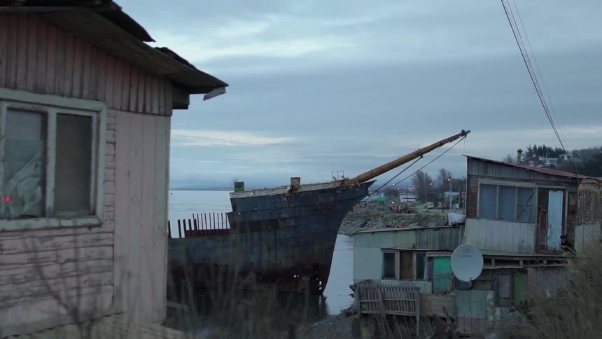 Boat sits in the water next to a dilapidated building