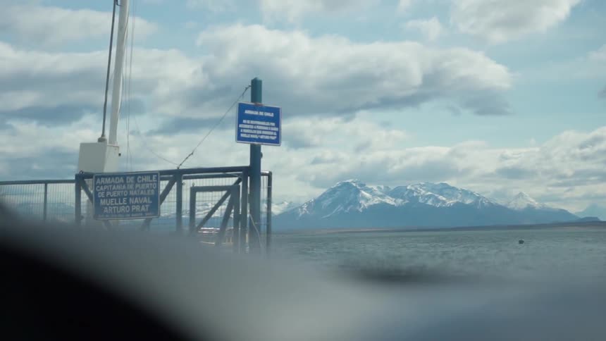 A large ship can be seen in the water from the car