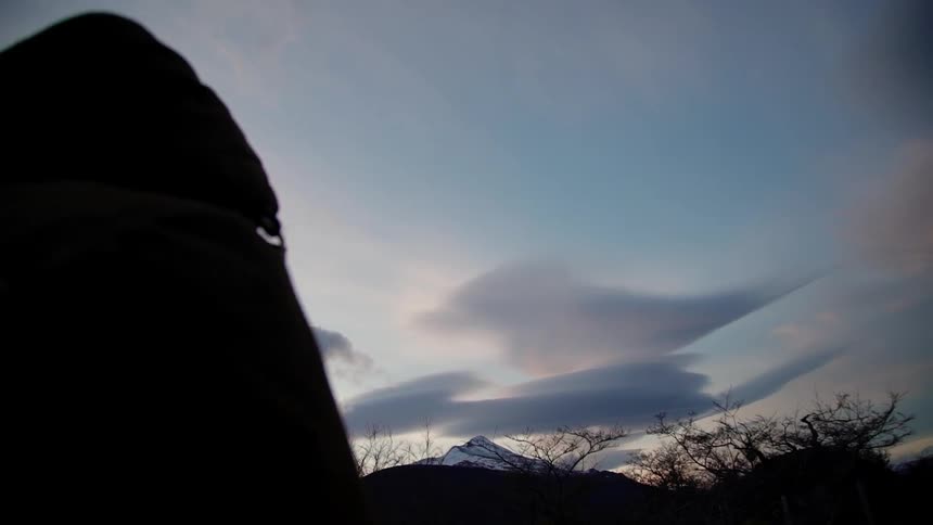 Person walks near hilly land at sunset