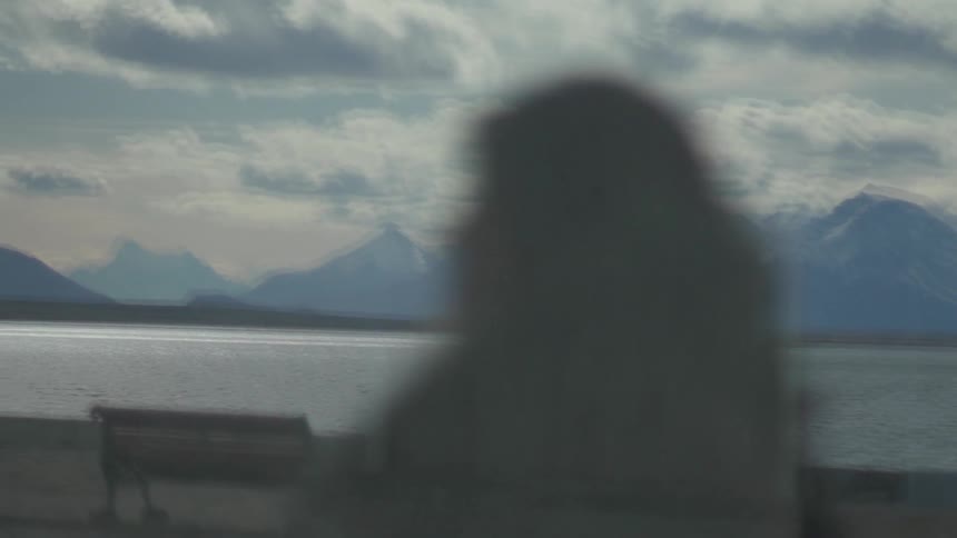 A person walks past benches near the water