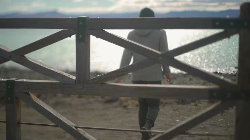 Man climbs over a fence and walks towards the lake