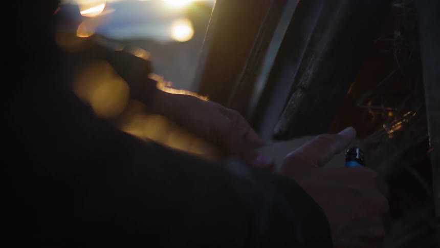 A person is trying to use a lighter to a fire at dusk
