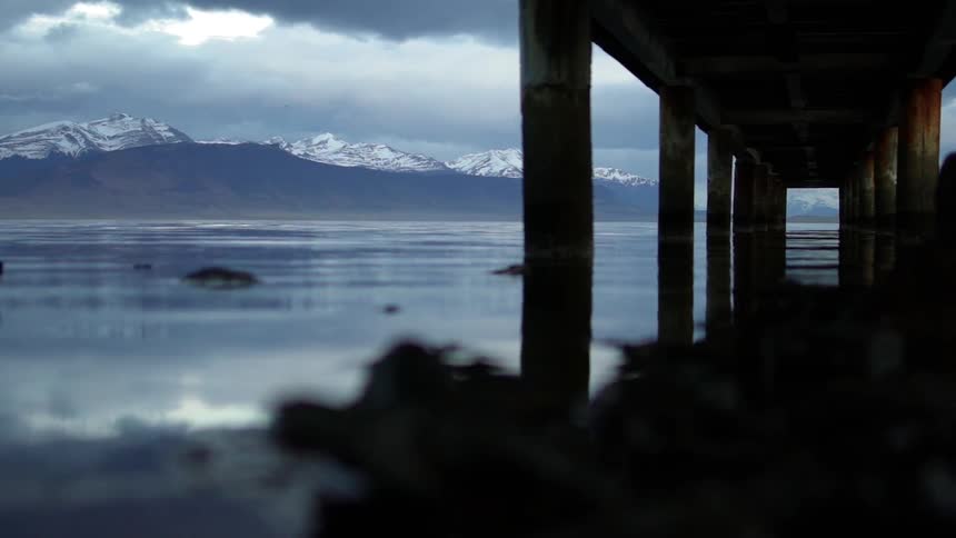 Pylons from a pier are reflected on the water surface