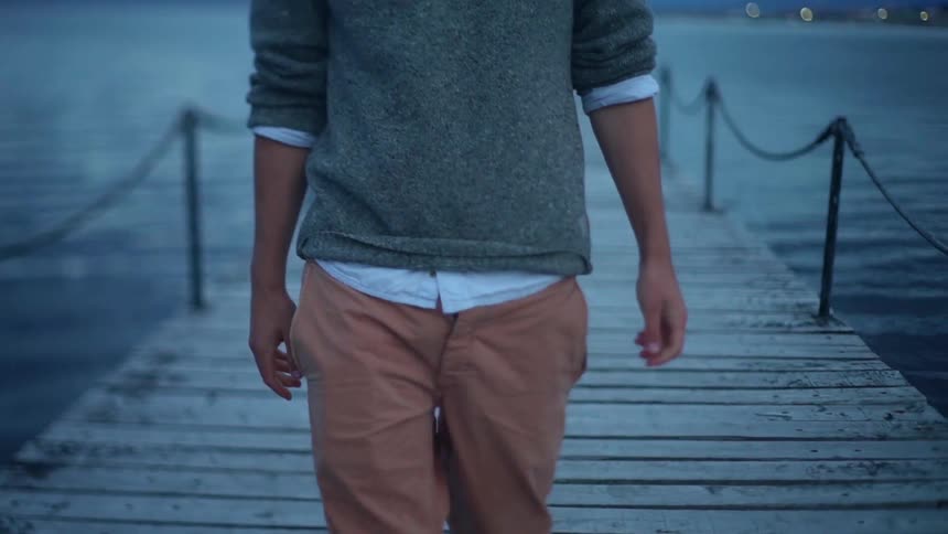 A man walks on a lake dock at sunset